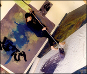 Artist Brenda Heim guiding a large mop soaked with paint across a 12 foot canvas on the studio floor.