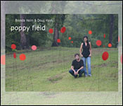 Artists Brenda Heim and Doug Hays on a hilltop with their public art installation, 100 metal red dots on metal sticks planted around them.